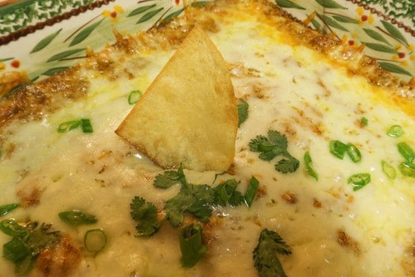 Irresistible Mexican Hot Bean Dip cooked in a green casserole.