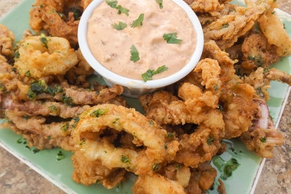 Fried Calamari with Creamy Chipotle Sauce served on a green platter.