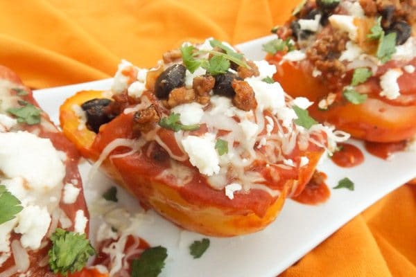 Mexican Stuffed Peppers topped with queso fresco, monterey cheese, cilantro and served on a white platter.