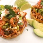 Chicken Sopes topped with all the goodies and served on a white platter with avocado slices and lime.