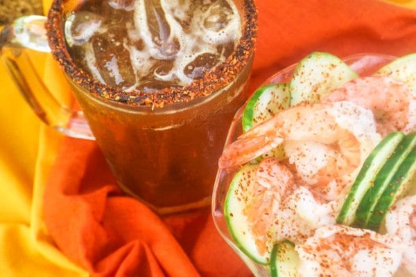 Mexican Michelada served in a beer mug with cocktail shrimp beside it in a bowl.