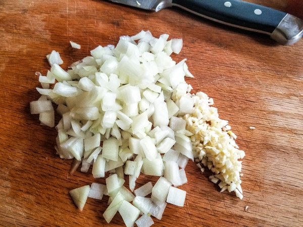 Chopped onions and garlic on wooden board for Albondigas en Salsa de Chipotle