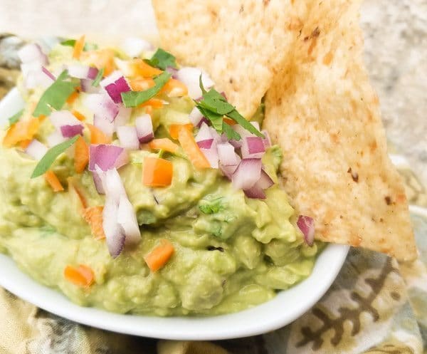 Authentic Mexican Guacamole Recipe made with habanero peppers and served in white dip bowl with tortilla chips.
