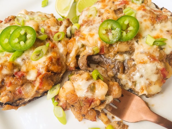 The best Stuffed Mushrooms Recipe!  Made with scallops, onions, tomato, jalapeños, heavy cream, butter, pepper jack cheese and fresh bread crumbs.  Moist, creamy and hyper delicious! Served on a white platter.