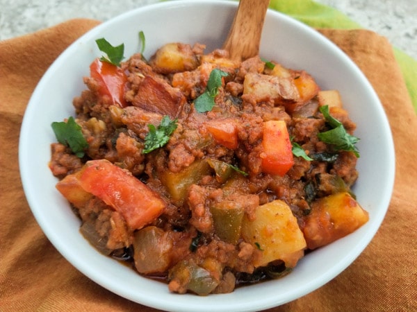 Authentic Mexican Picadillo Recipe with potatoes, tomatoes, onions, peppers and garlic topped on white rice.