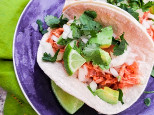 These Tacos de Tinga are made with shredded chicken, tomatoes, onions, garlic, chipotle peppers in adobo sauce, served in corn tortillas and topped with chopped onions, fresh chopped cilantro and avocado cubes.