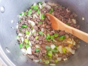 Ground venison cooking in pot with peppers, onions, jalapenos and garlic.