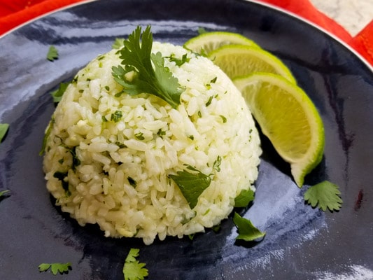Cilantro Lime Rice served on a blue platter with lime wedges.
