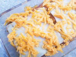 Pastelón topped with shredded cheese about to go into the oven to bake.