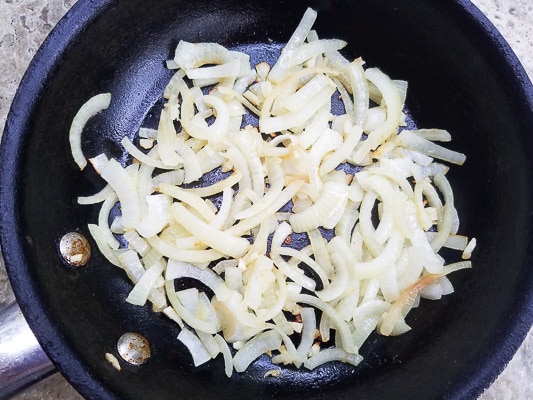 Onions sauteing in a black skillet for the Avocado and Chipotle Mushroom Tostadas.