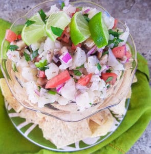 Cauliflower Ceviche served in a glass bowl with tortilla chips and lime wedges.