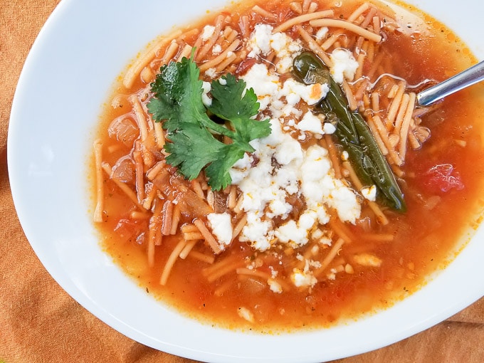 Sopa de Fideo served in a white bowl and topped with queso fresco and fresh cilantro.