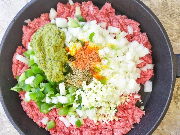 Raw ground meat with onions, peppers, sofrito, garlic and spices in a cast iron skillet ready to cook. - Carne Molida (Puerto Rican Picadillo)