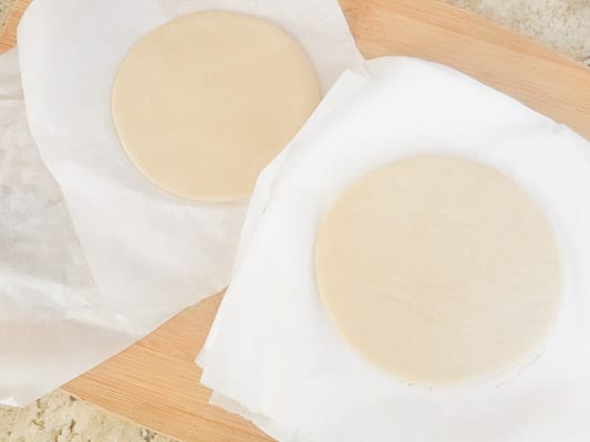 Raw empanadillas discs in between parchment squares for storage.-Masa Para Empanadillas (Dough for Empanadillas)