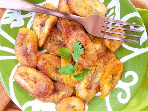 Platanos Fritos (Puerto Rican Sweet Plantains) cooked and serve on a green and white plate.