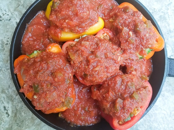 Salsa Criolla topped on peppers in a cast iron skillet.
