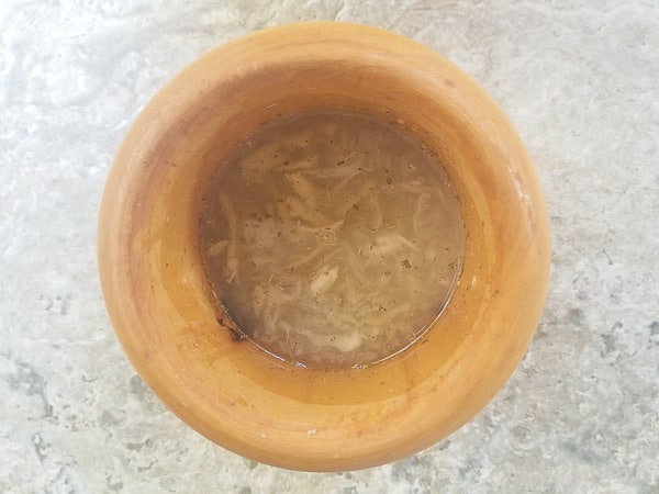 Garlic, oregano and vinegar in a wooden mortar and pestle.