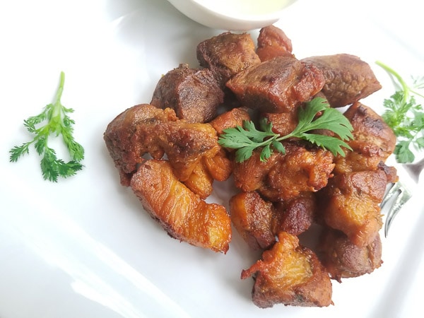 Delicious Pork Chunks served with a side of garlic sauce on a white platter.
