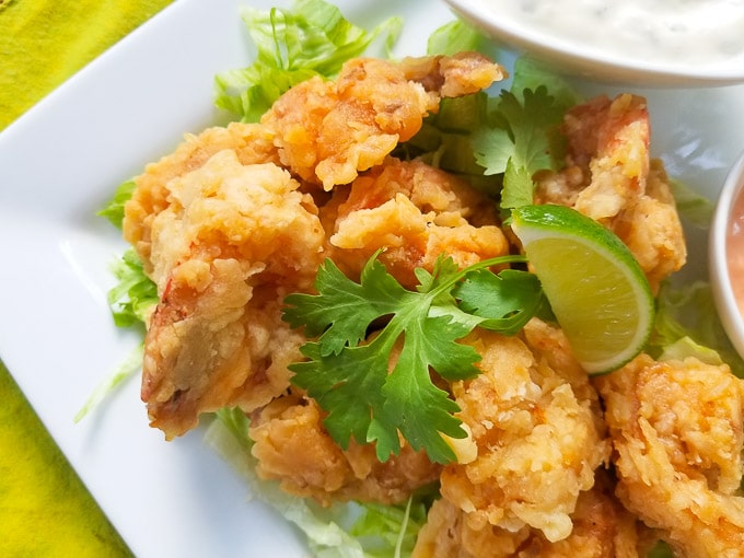 Camarones Empanizados (Battered Shrimp) served with jalapeno mayo sauce, mayo-ketchup with lime wedges on a white platter.