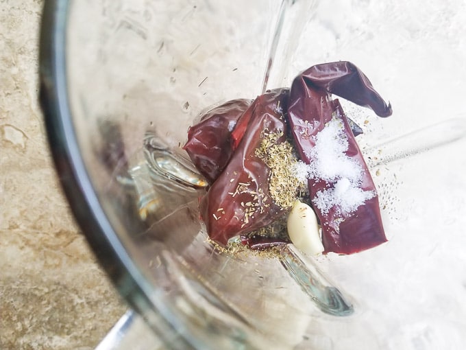 Guajillo peppers in a blender with garlic, oregano, salt and water.