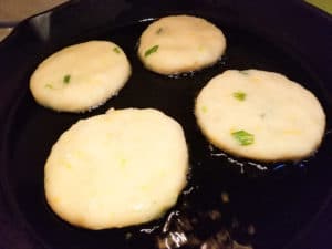 Tortitas frying in a cast iron skillet.