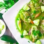 Fully assembled aguachile de camaron platter topped with onions, avocado and cucumbers.