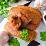 Alcapurrias (alcapurrias puertorriqueñas) served on a white platter with hot sauce.