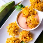 Arañitas de Platano Verde served on a white platter with a side of mayoketchup.