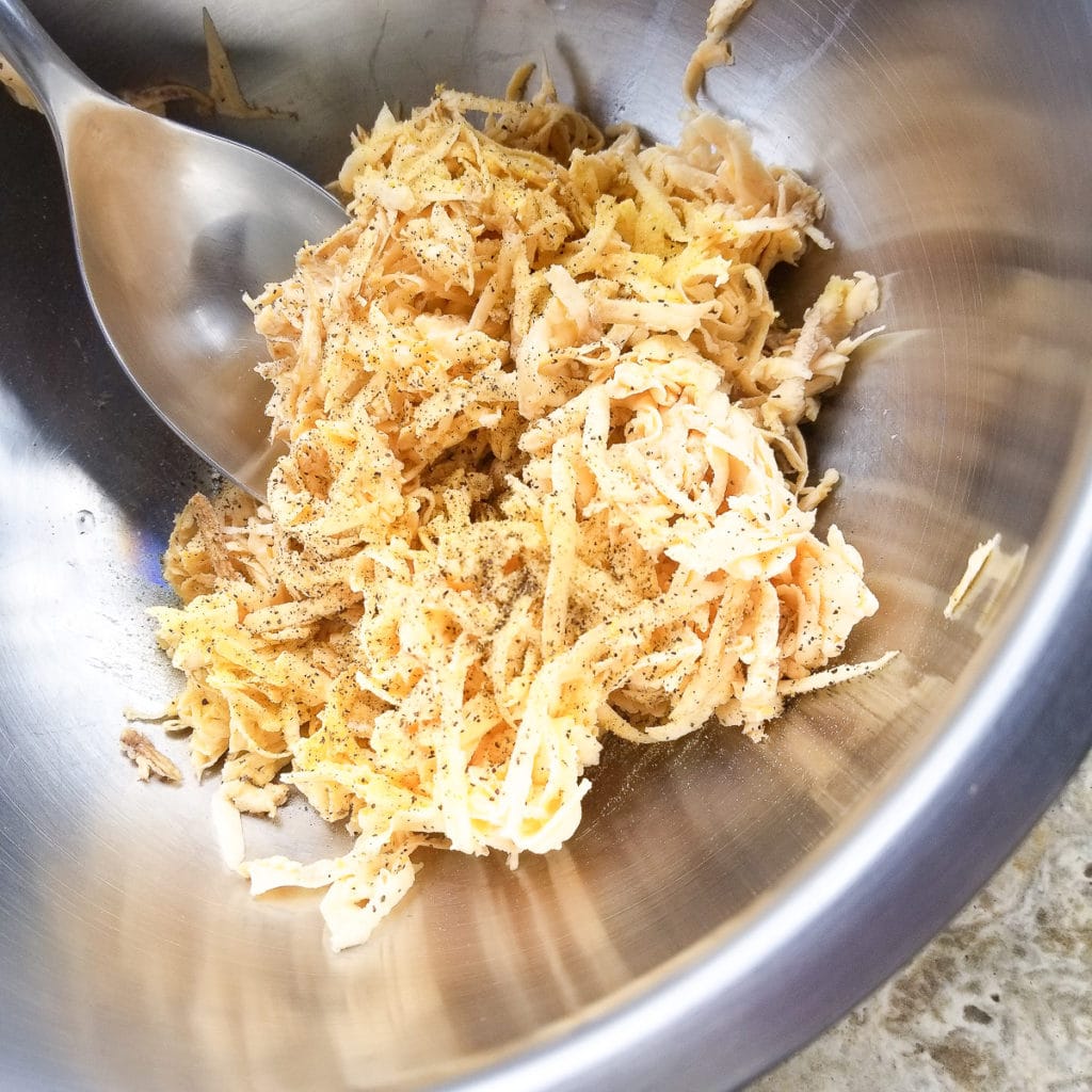 Shredded plantains in a mixing bowl with seasonings.