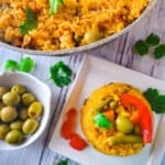 Arroz a la Jardinera (Arroz con Vegetales) cooked in a cast aluminum pot, (caldero), a side of olives and a serving of rice.