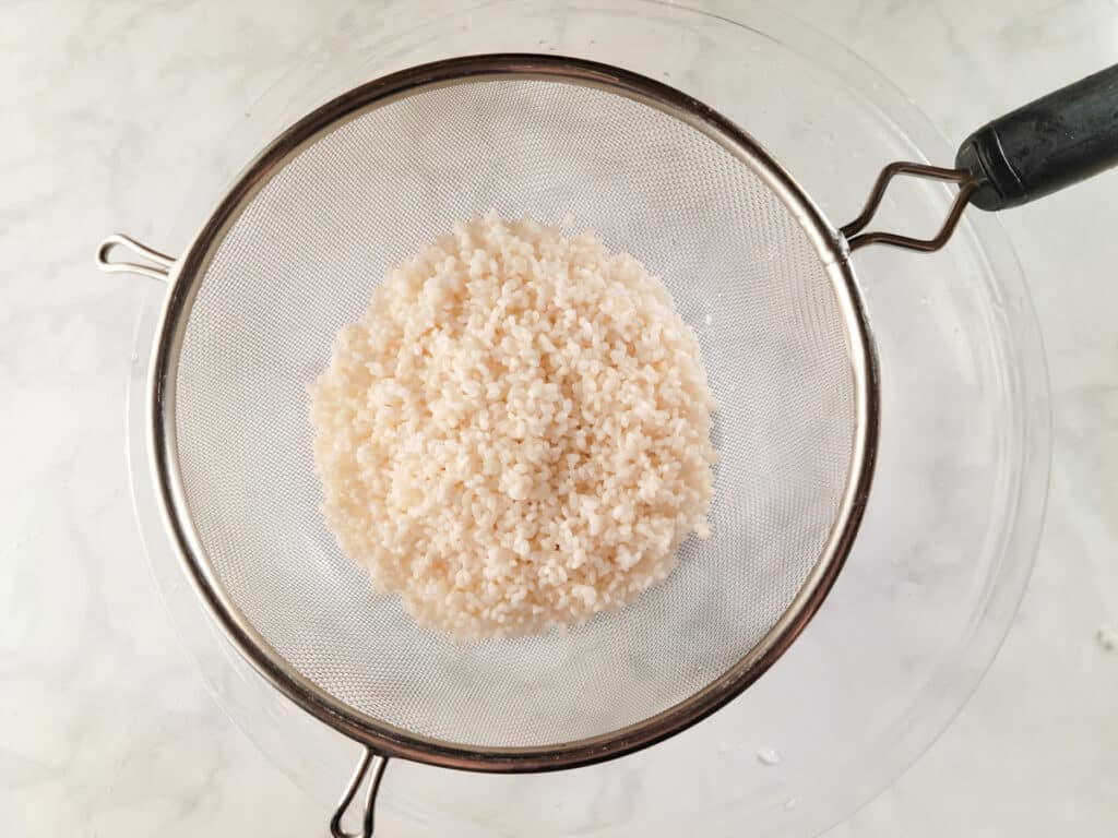 Rinsing rice through a strainer.