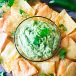 Avocado Cilantro Sauce served in a glass bowl surrounded by freshly made tortilla chips.