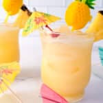 Two Bacardi Pina Coladas served in glasses, topped with maraschino cherries, pineapple slivers and straw.