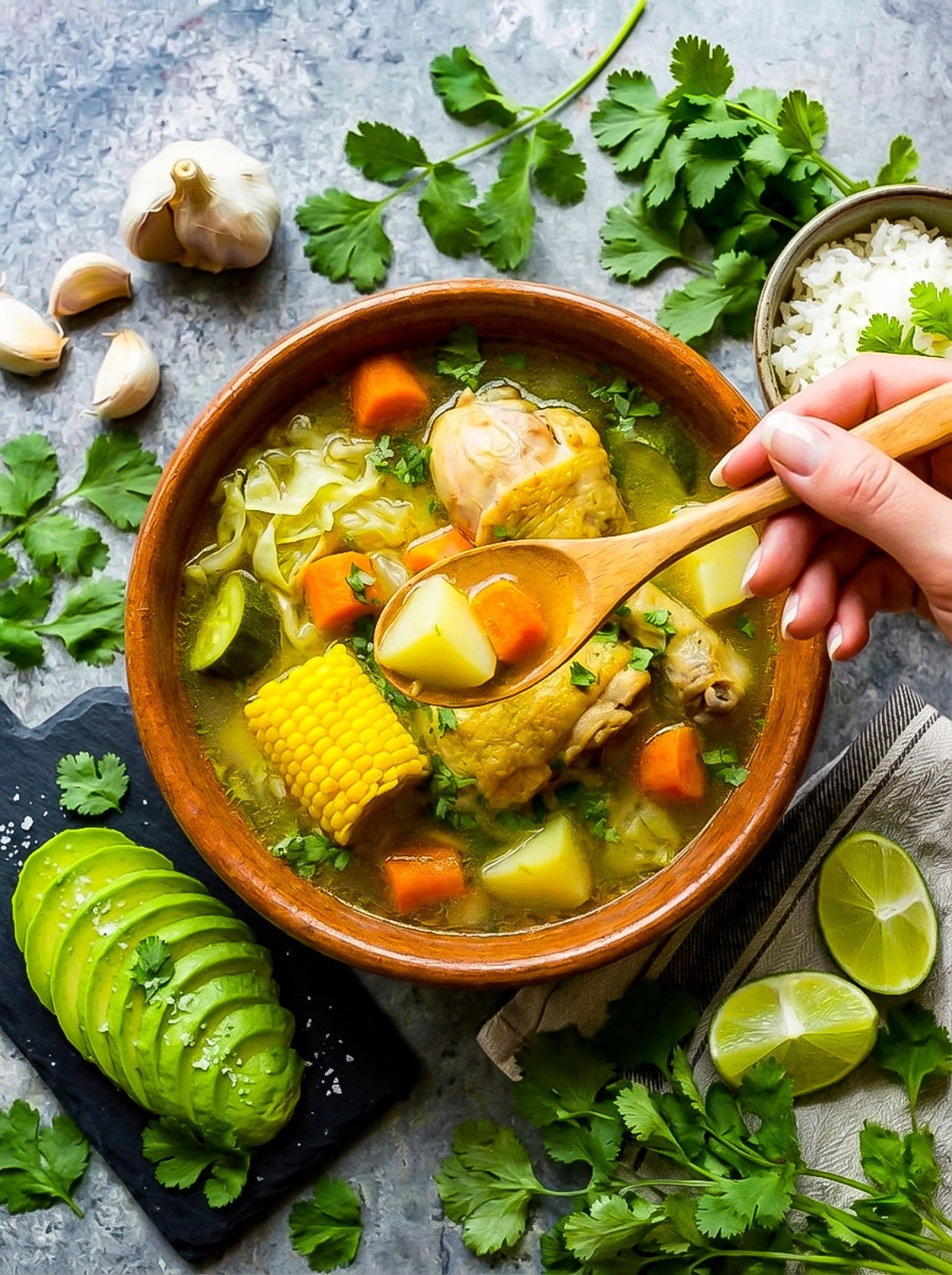 Caldo de Pollo (Mexican Chicken Soup) with carrots, onion, green cabbage, corn cob pieces and jalapenos served in a Mexican clay bowl.