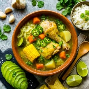Caldo de Pollo (Mexican Chicken Soup) with carrots, onion, green cabbage, corn cob pieces and jalapenos served in a Mexican clay bowl.