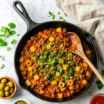 Carne Molida (Puerto Rican picadillo) cooked in a black cast iron skillet.