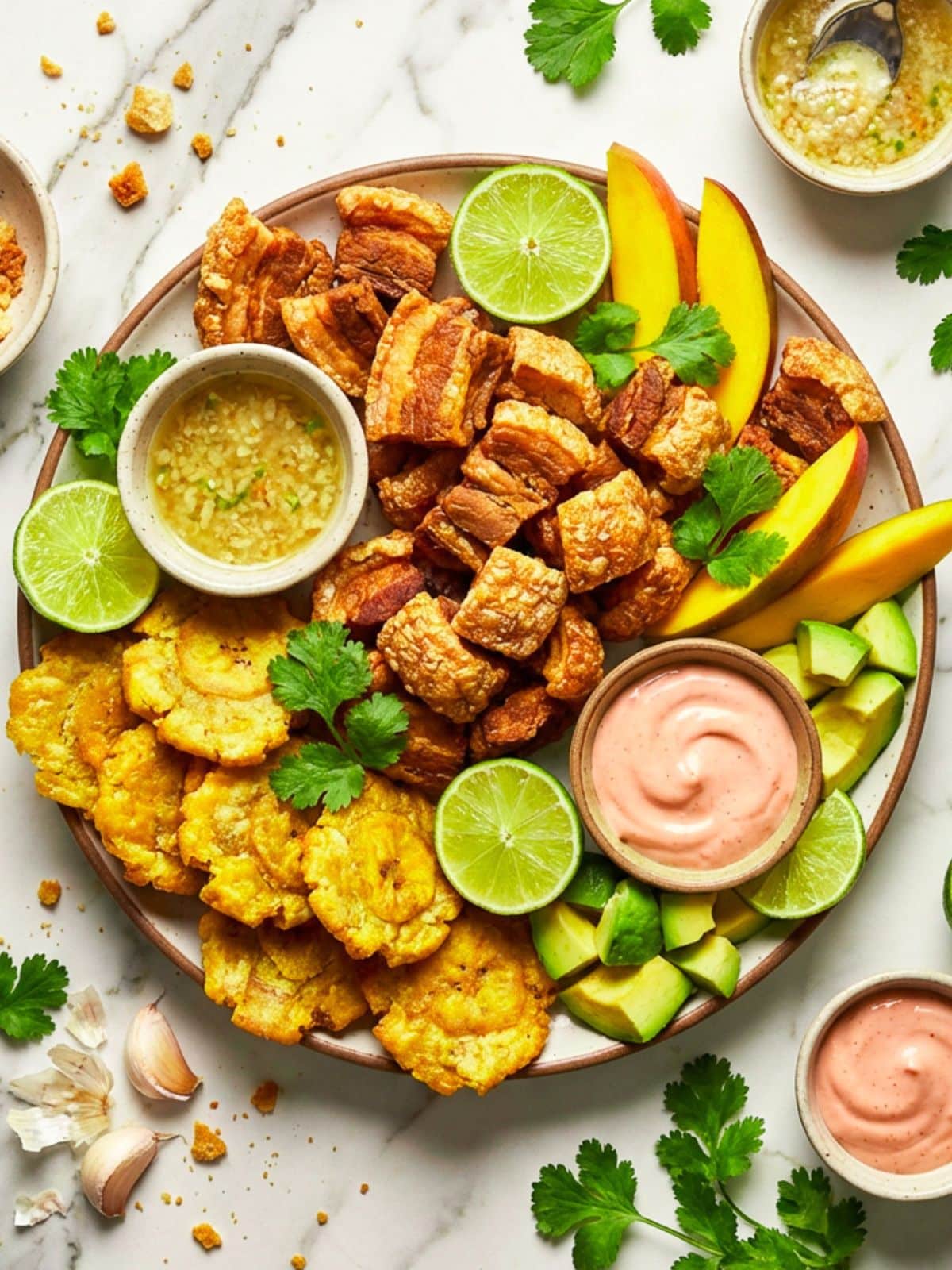 A large platter of chicharrones, tostones, sliced avocados and lime wedges charcuterie serving.