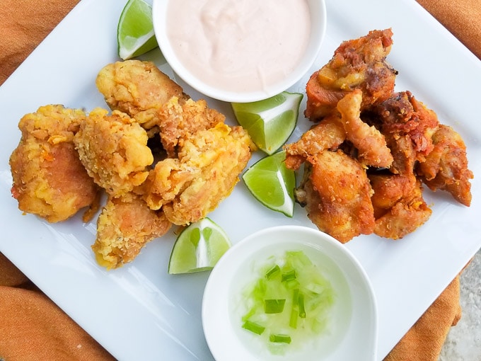 Chicharrones de Pollo served alongside white rice, Puerto Rican stewed beans and lime wedges.