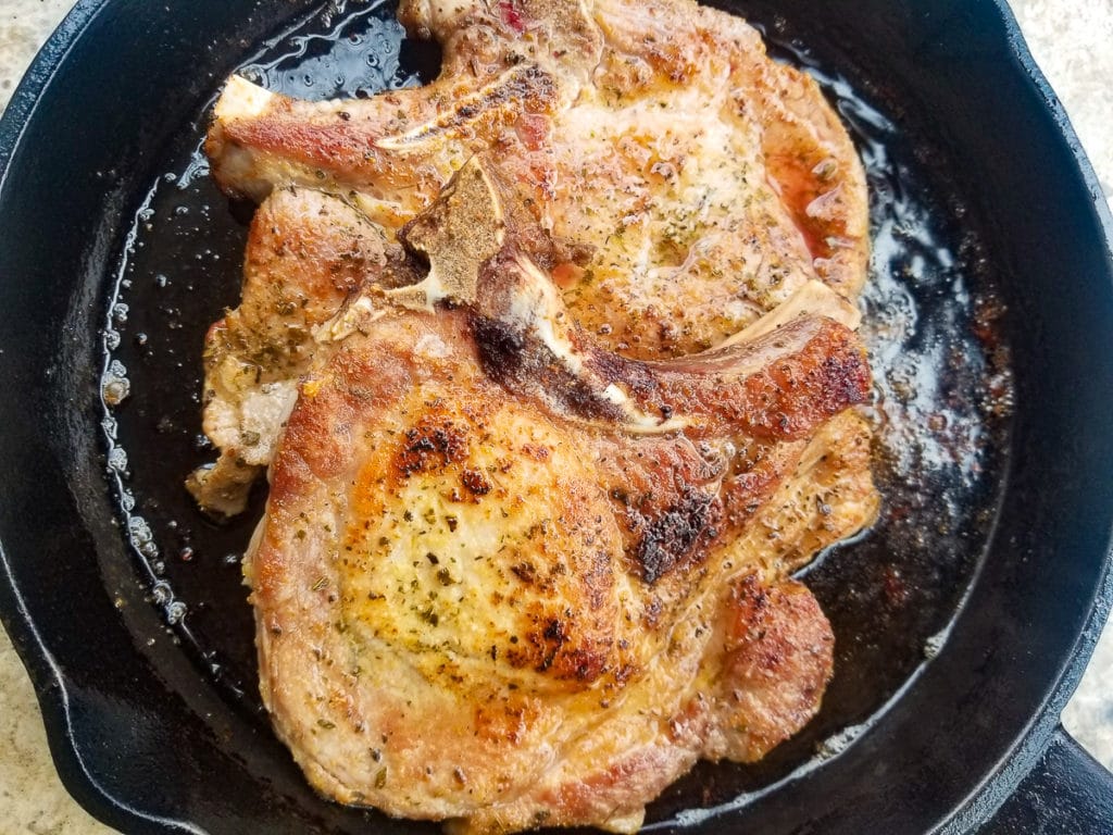 Cooked pork chops in a cast iron skillet.