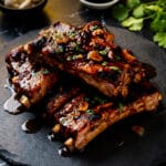 Costillas de Puerco served on a black slate and topped with chopped cilantro.