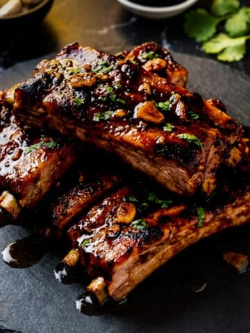 Costillas de Puerco served on a black slate and topped with chopped cilantro.