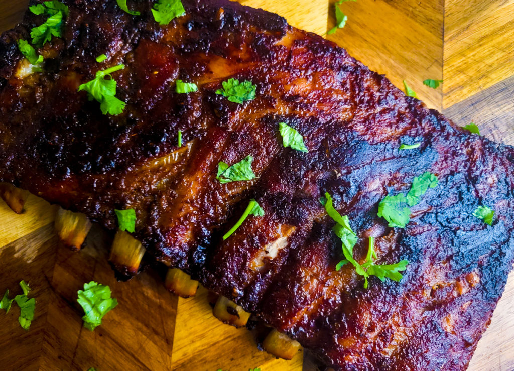 Fully cooked Costillas de Puerco (Pork Spare Ribs) on a wooden cutting board.
