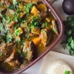 Costillas en salsa verde cooked in a large saucepan with a side of white rice and avocado.