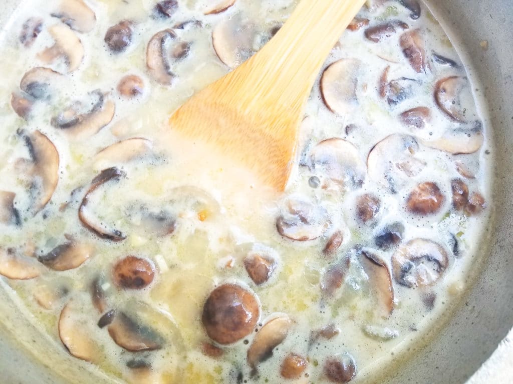 Chicken broth, milk and seasonings added to pot for crema de hongos.