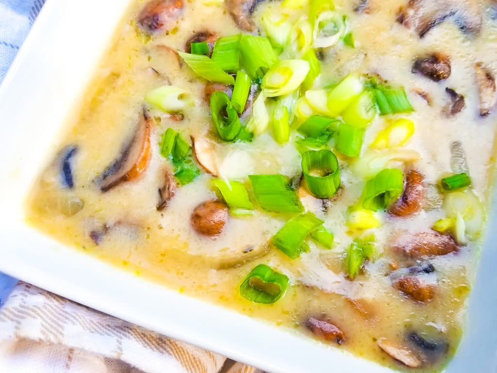 Crema de Hongos (Crema de Champinones), mushroom soup in a white bowl topped with chopped scallions.