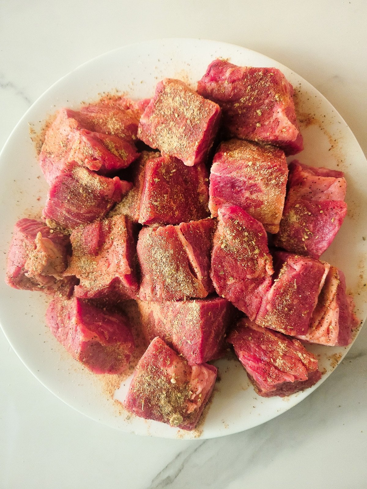 Seasoned beef chucks on a white plate.