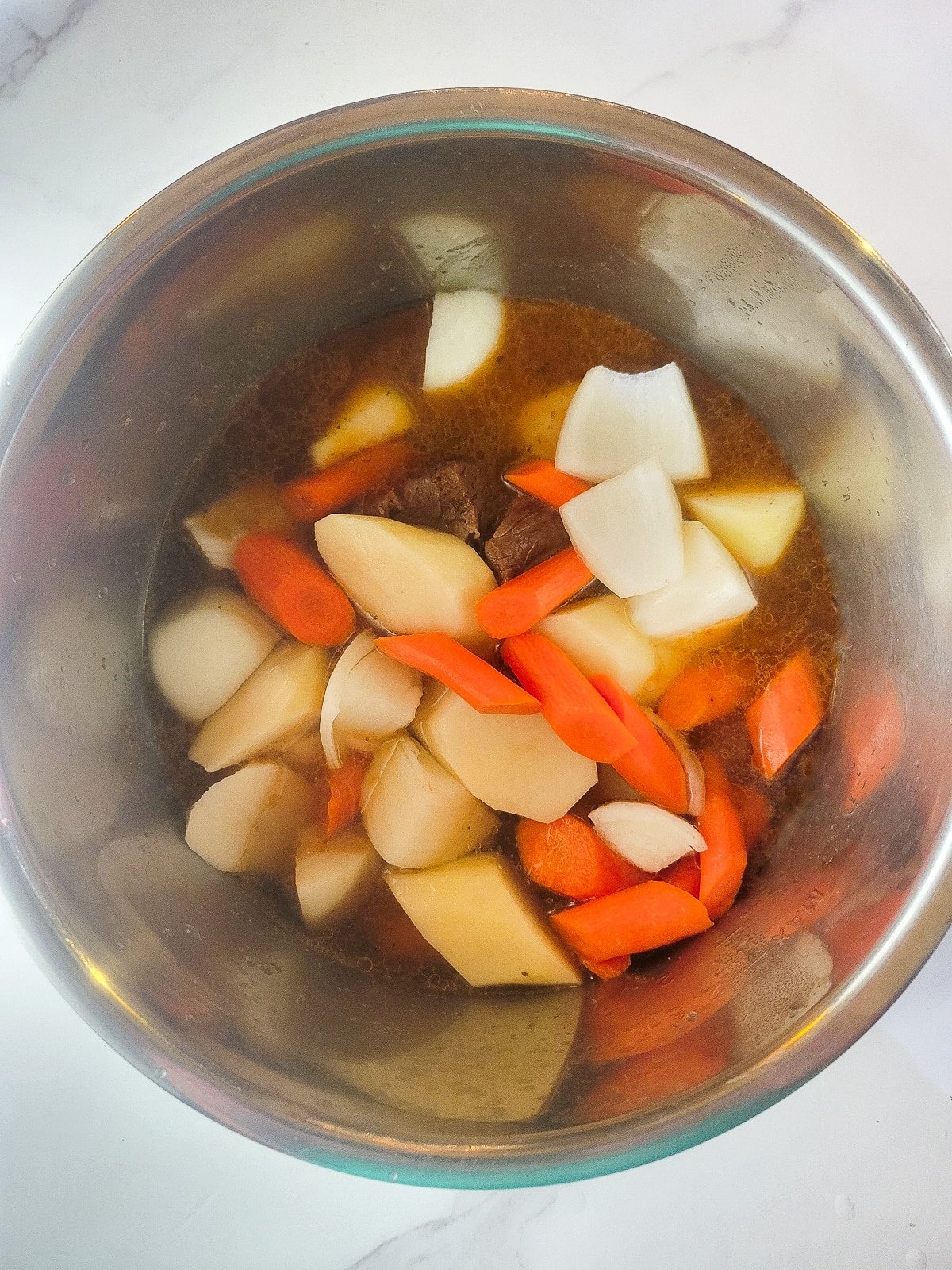 Beef chunks, potatoes, carrots, onions and broth in Instant Pot.