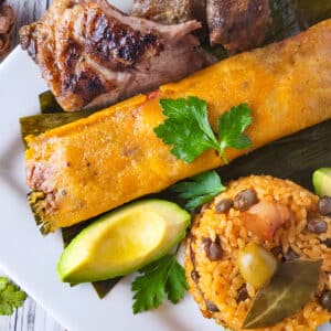 Empanadas de Yuca served on a plate with a side of arroz con gandules, pernil and a side of avocado.