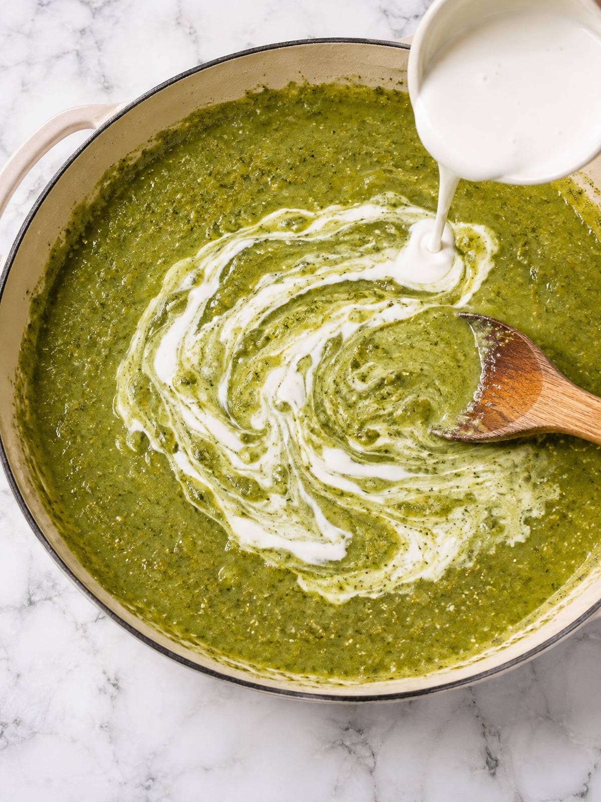 Sauteing the salsa verde in a skillet while mixing in the Mexican crema together.