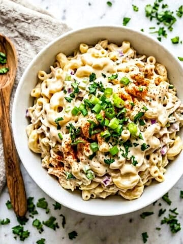 Ensalada de Coditos served in a white bowl with a wooden serving spoon beside the bowl.